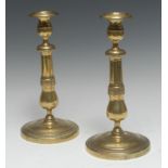 A pair of large French Empire brass table candlesticks, campana sconces with detachable nozzles,