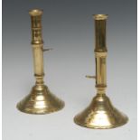 A matched pair of early 18th century brass ejector candlesticks, flared sconces,