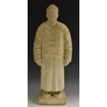 A Chinese marble figure, carved as a man in a traditional tunic and fur hat, rectangular base, 57.