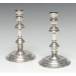 A pair of George I style silver table candlesticks, waisted sconces, knopped pillars,