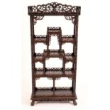 A Chinese hardwood open vitrine, shaped cresting above an arrangement of galleried display plateaux,