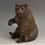 A Black Forest model of a bear, seated, with paw raised, glass eyes, 14.5cm high, c.