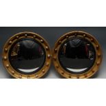 A pair Regency design giltwood and gesso circular convex looking glasses,