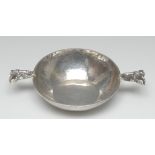 An Arts and Crafts silver wine taster, caprine mask lug handles, planished bowl, 16cm wide,