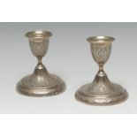 A pair of Iranian silver coloured metal candlesticks,