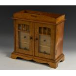 A Secessionist oak table cabinet, the architectural pediment inlaid with three copper lozenges,