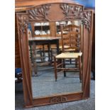 An Art Nouveau oak looking-glass, the frame carved in relief with sprigs of mistletoe,
