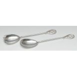 A pair of Art Nouveau silver fruit spoons, the long hafts with sinuous terminals,
