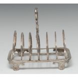 A George IV silver seven-bar toast rack, lotus-grasped loop handle, arched double-scroll divisions,
