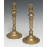 A pair of French Empire brass candlesticks, campana sconces, knopped stems,