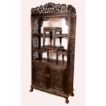 A Chinese hardwood display cabinet, shaped cresting above an asymmetrical arrangement of shelves,