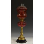 A 19th century cranberry glass and gilt-patinated bronze oil lamp, circular ebonised base,