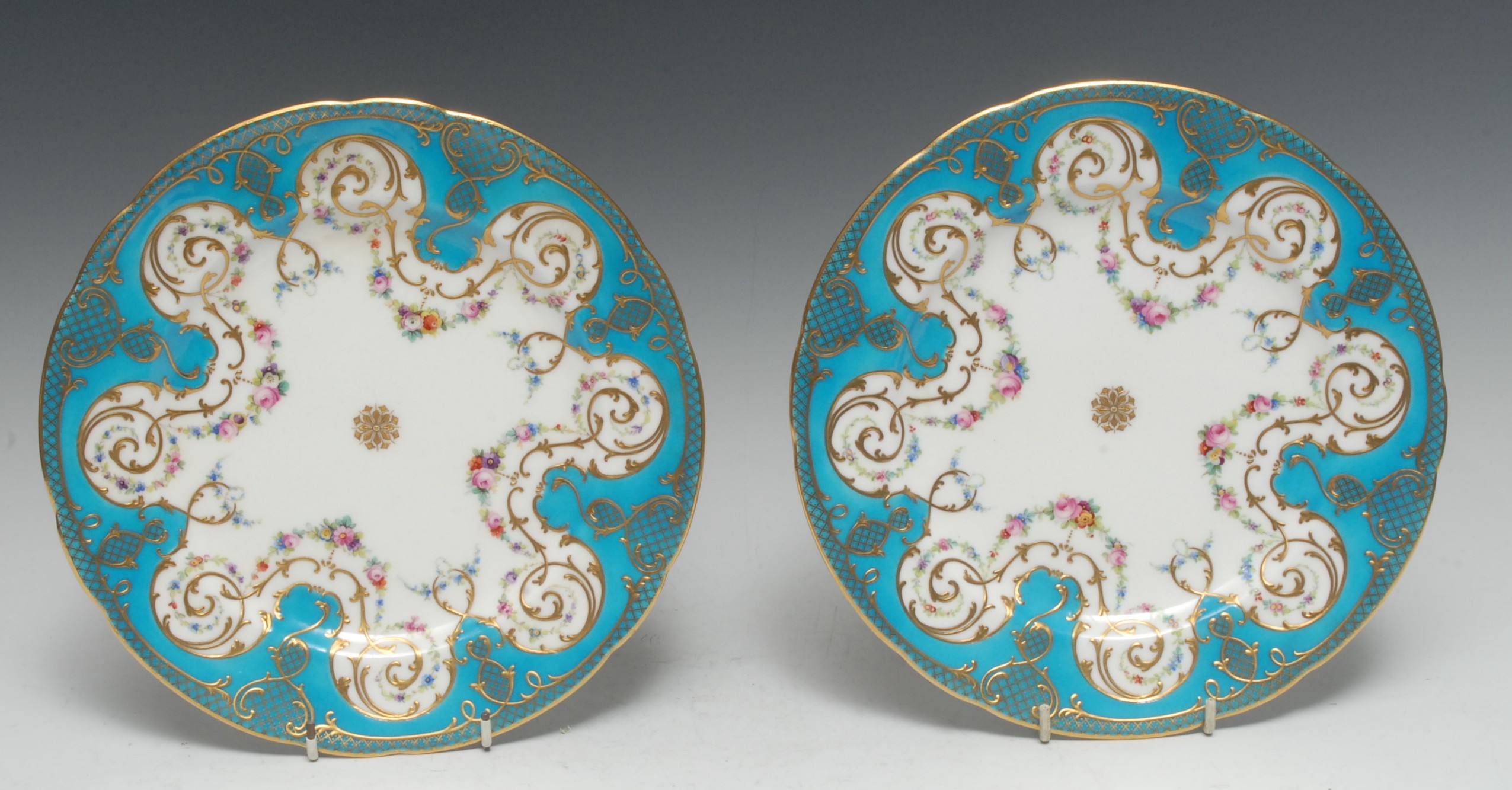 A pair of Minton shaped circular cabinet plates, painted with swags of colourful flowers,