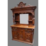 A late 19th century Flemish oak sideboard, outswept cornice above a mirror and a pair of shelves,