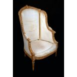 A Louis XVI style wingback armchair, carved throughout with ribbons and scrolling acanthus,