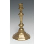 An early 18th century French brass octagonal candlestick, chased with flowers,