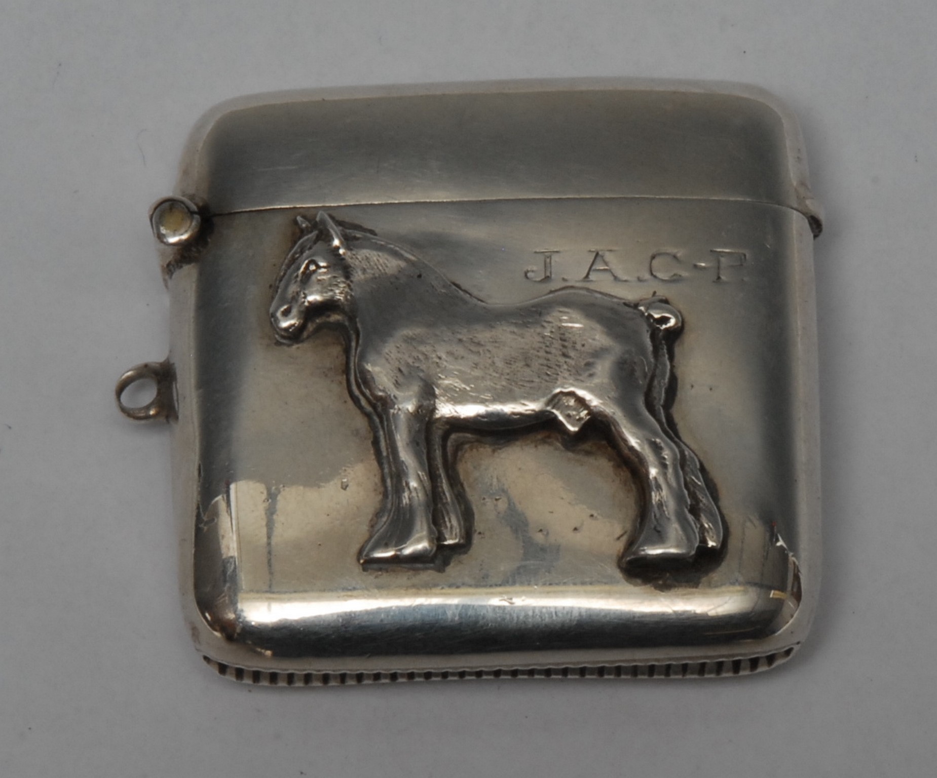 A George V silver rounded rectangular vesta case, applied with a shire horse, hinged cover,