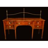A George III mahogany shaped serpentine sideboard, brass rail gallery with urnular finials,