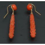 A pair of tubular carved bomb drop coral earrings, gold coloured metal fittings, hook pillars,
