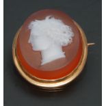 A 19th century carnelian hardstone cameo brooch, carved with a neoclassical ladies head to dexter,