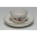 A Derby tea bowl and saucer, painted in polychrome enamels with scattered flowers and leafy foliage,