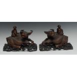 A pair of Chinese hardwood carvings, of boys astride the backs of water buffaloes, inset glass eyes,