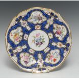 A rare Derby shaped circular plate, painted in Worcester style with fan and vase shaped reserves,