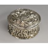 An Edwardian silver shaped circular dressing table trinket box, profusely chased with flowers,