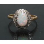 A diamond and opal cluster ring, central oval opal cabochon flashing vibrant red, green,