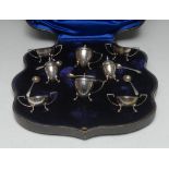 A George V eight piece silver cruet set, shaped rims, C-scroll and hoof feet,