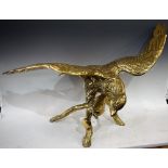 A large solid brass model of an eagle, perched on a branch with wings outstretched, 90cm wing span,