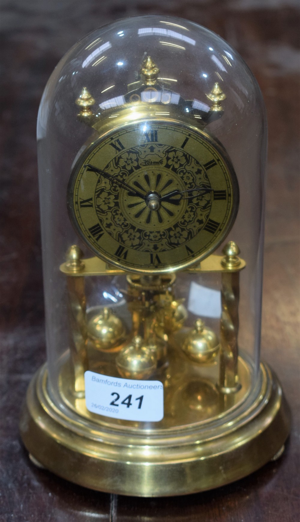 A Hermle brass anniversary clock, of small proportions, glass dome,