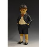 A mid 20th century composite doll, of a school boy with stubborn demeanor, hands in pockets,