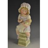 A Gebruder Heubach bisque figure, little girl seated playing with her doll, wearing a pretty dress,