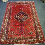 A hand woven MIddle Eastern rug, central lozenge motif, geometric designs in hues of sienna,