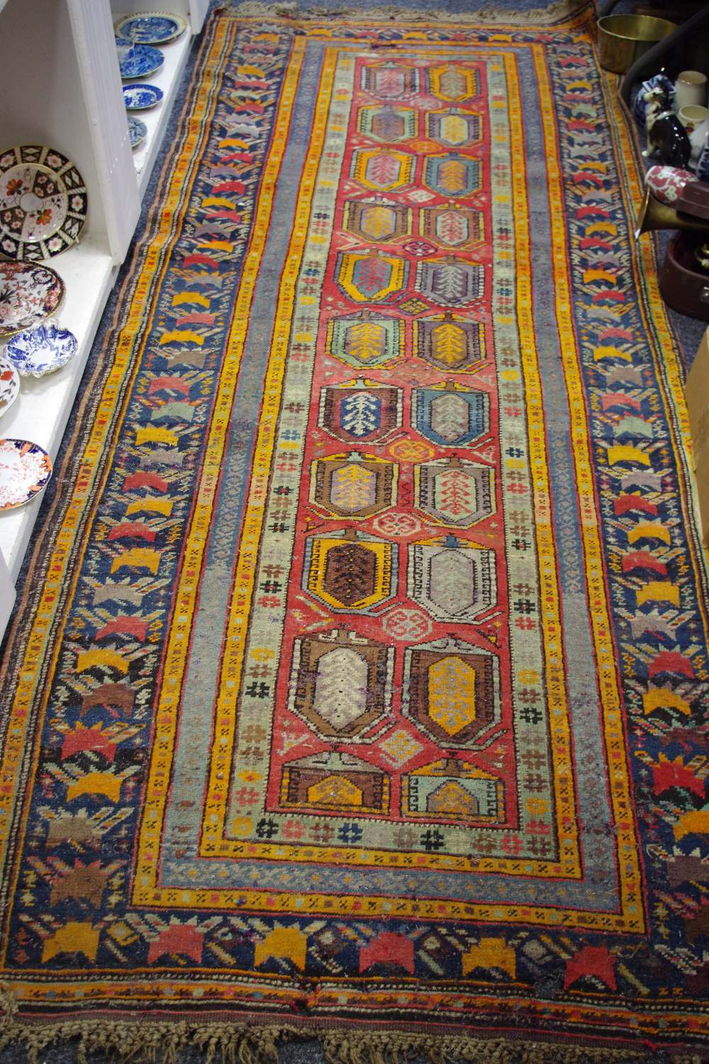 A Middle Eastern hand woven runner, geometric designs in tones of sienna,