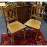A pair of oak hall chairs, pierced and shaped top rail, reeded uprights, shaped X-frame splat,