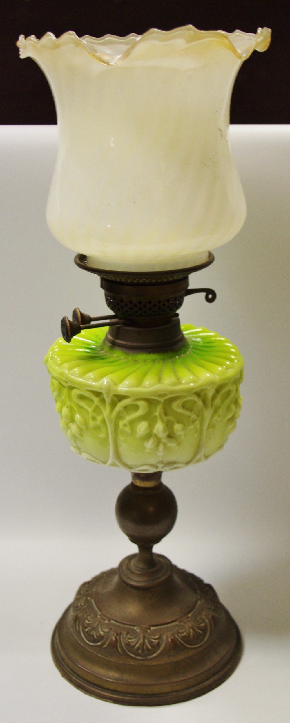 A Victorian Art Nouveau oil lamp, milk glass reservoir in tones of green,