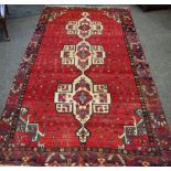 A hand woven Turkman carpet, three beige medallions decorated with geometric shapes on a red ground.