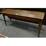 An oak window seat, canted rectangular top, shaped apron, turned spreading supports,