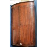 A George III mahogany bow-front corner cupboard,