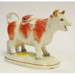 An early 20th century cow creamer and cover, with rust markings, oval base,