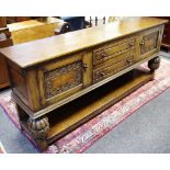 A Priory style oak sideboard, oversailing top, two drawers flanked by carved panel door cupboards,