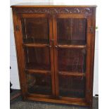 An oak floor standing book case, moulded top, carved frieze, two glazed doors enclosing shelving,