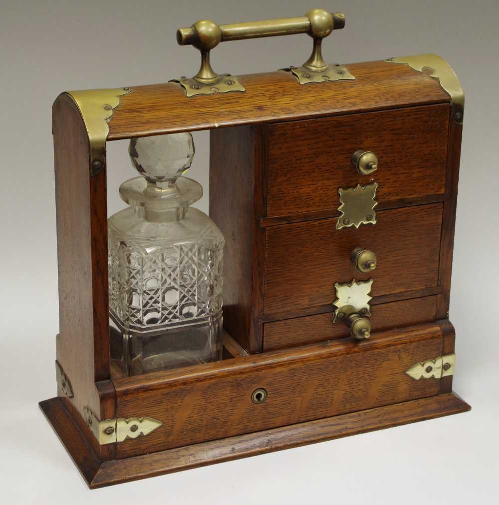 A Victorian oak Tantalus single bottle flanked by a trio of drawers c.