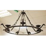 A wrought iron seven light chandelier with stylised ram head terminals