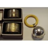 A silver babies teething ball rattle, cream teething ring, Birmingham 1954; a silver napkin ring,
