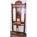 A late Victorian mahogany hall stand, shaped top rail, rectangular mirror flanked by coat pegs.