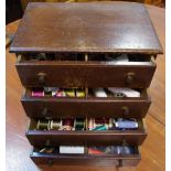 An early 20th century miniature four drawer chest containing sewing equipment