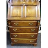 A modern oak bureau of small proportions,